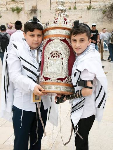 Two boys holding a Torah scroll at the Western Wall during a Bar Mitzvah celebration