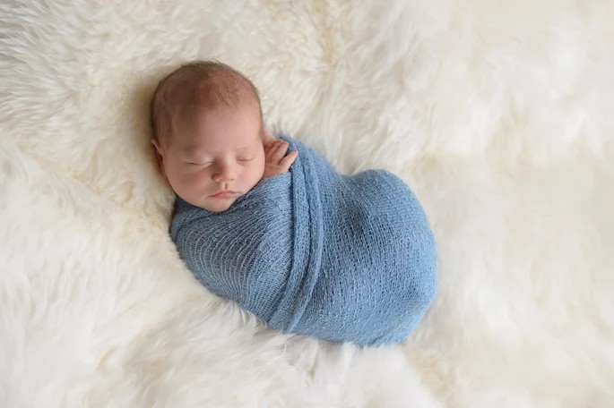 A newborn baby swaddled in a blue wrap, resting ahead of his Bris Milah